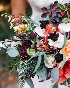 a bride holding a bouquet of flowers and greenery