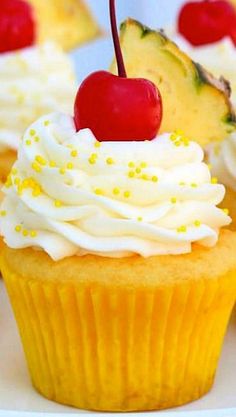 cupcakes with white frosting and cherries on top, topped with pineapple slices