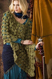 a woman in a green crocheted shawl and blue dress holding a guitar