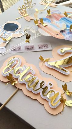 a table topped with lots of paper cut outs and gold foil letters that spell out the word bride