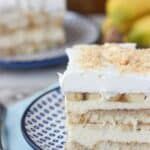 a piece of cake sitting on top of a blue and white plate with bananas in the background