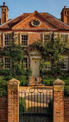 a large brick house with an iron gate and ivy covered trees on the front door