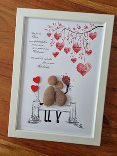 two rocks sitting on top of a bench under a tree with hearts hanging from it