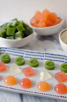 small candy candies on a plate with bowls of green and orange gummy bears