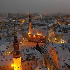 an aerial view of a city at night with snow on the ground and buildings lit up