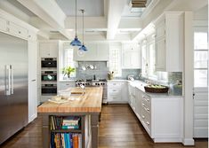 a large kitchen with white cabinets and wooden counter tops, along with stainless steel appliances