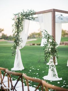 an outdoor ceremony setup with white flowers and greenery