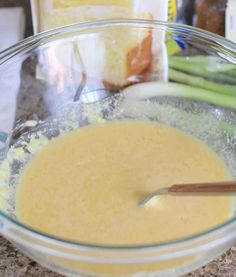 a glass bowl filled with batter next to green beans and carrots on top of a counter