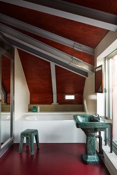 a bath room with a tub a sink and a stool next to a large window