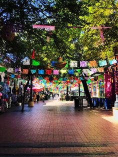 an outdoor market with lots of colorful items hanging from the trees