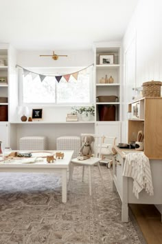 a living room filled with furniture and lots of white shelves next to a window on top of a wooden floor