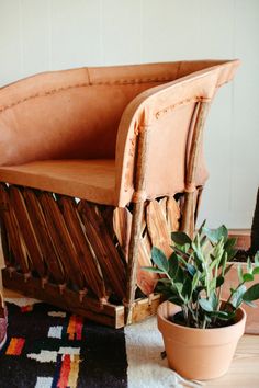 a wooden chair sitting on top of a rug next to a potted plant in front of it