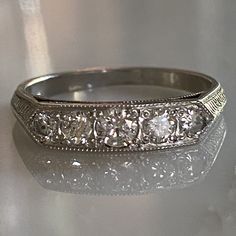 Details: Sweet vintage inspired Art Deco Style diamond and platinum half round eternity ring. This ring was designed by our amazing jeweler, and has lovely vintage diamonds. You'll be pleased to add this beauty to your collection. Would look great in a ring stack! This ring comes with an appraisal. Appraisal: One (1) platinum diamond band. Bead set across the top, graduating out from the center are five (5) round brilliant cut diamonds, measuring 3.4 - 2.5 mm, weighing approximately 0.45 carat c Art Deco Band, Formal Eternity Band With Rose Cut Diamonds, Anniversary Platinum Rose Cut Diamond Ring, Classic Eternity Band With Rose Cut Diamonds For Promise, Anniversary Platinum Diamond Ring With Rose Cut Diamonds, Anniversary Rose Cut Diamond Platinum Ring, Anniversary Platinum Ring With Rose Cut Diamonds, Platinum Rose Cut Diamond Ring For Anniversary, Classic Diamond White Diamond Ring For Marriage