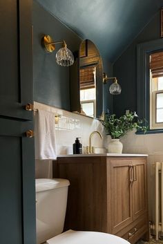 a white toilet sitting next to a wooden cabinet in a bathroom on top of a tiled floor