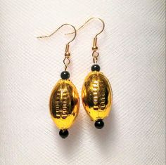 These are acrylic bright gold football beads with black glass accent beads at both ends. These are perfect gifts or presents for all of us football lovers!! These are plastic so they are pretty light earrings. The colors also match the New Orleans Saints and Southern Miss college football team colors. Accent Earrings, Football Jewelry, Gold Football, College Football Teams, Team Mascots, Trendy Mom, Light Earrings, Fan Earrings, Pretty Lights