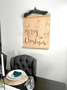 a dining room table set for christmas with place settings and decorations on the wall above it