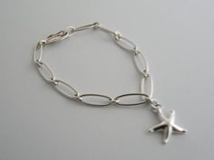 Overview:Offered for sale is a wonderful and gorgeous Tiffany and Co. Sterling Silver Peretti Starfish Link Bracelet.   The piece is made from bright Tiffany sterling silver, yet has a very delicate and feminine feel to it.  Hanging from its Tiffany Sterling Silver link chain is a whimsical and very pretty starfish.   The piece is quite hard to find and come by,  so grab it while you have the chance!  It is very pretty worn on its own, but would also work very well with other jewelry that you al Tiffany And Co Bracelet, Silver Link Chain, Dinner With Friends, Silver Chain Bracelet, Tiffany And Co, Gift Pouch, Bracelet Bangle, Link Chain, Tiffany & Co.