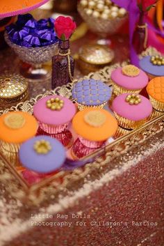 colorful cupcakes are displayed on a table with other decorations and decorating items