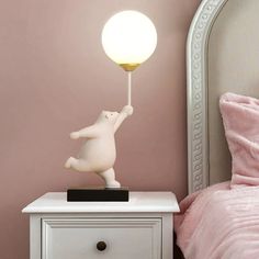 a white teddy bear lamp sitting on top of a nightstand next to a pink bed