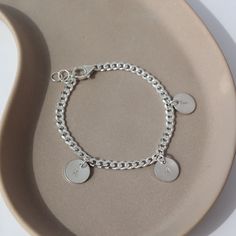 925 sterling silver Carter Personalized disc Bracelet laid on a gray plate in the sunlight. This bracelet features the Carter chain then followed Initial stamped disc. Sterling Silver Initials Bracelet For Personalized Gift, Personalized Sterling Silver Initials Bracelet, Minimalist Sterling Silver Name Bracelet For Personalized Gift, Minimalist Sterling Silver Name Bracelet As Personalized Gift, Personalized Silver Charm Bracelet With Initials, Customizable Silver Name Bracelet For Friendship, Personalized Silver Bracelets With Initials, Customizable Silver Charm Bracelet For Friendship, Personalized Silver Bracelet With Initials