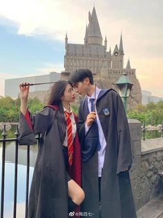 a man and woman dressed up in harry potter costumes standing next to each other near a castle