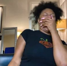 a woman covers her face with her hands as she sits on a couch in the living room