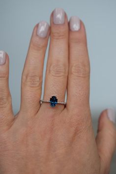 a woman's hand with a ring on it and a blue stone in the middle