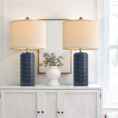 two lamps sitting on top of a white cabinet