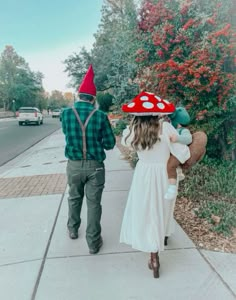 a man and woman are walking down the sidewalk with their child dressed up as mushrooms