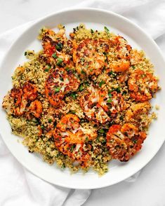 a white plate filled with shrimp and rice on top of a bed of vegetables next to a fork