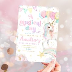 a hand holding up a birthday card with a unicorn on it and balloons in the background