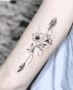 a black and white photo of a woman's arm with an arrow tattoo on it