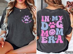 a woman sitting on top of a bed wearing a shirt that says in my dog mom era