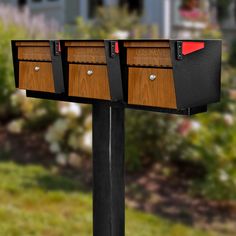 three mailboxes are shown on the side of a post in front of a house