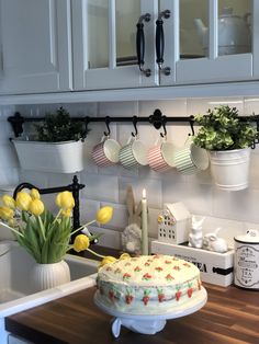 a cake sitting on top of a kitchen counter next to a vase filled with flowers