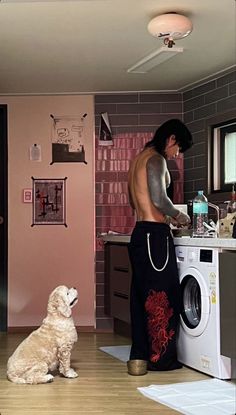 a man and his dog are in the kitchen with their washing machine on the floor