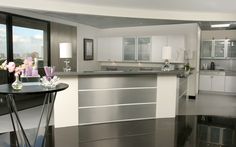 a modern kitchen with stainless steel appliances and black flooring is seen from across the room