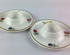 two white cups and saucers with berries on them