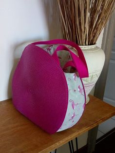 a pink and white bag sitting on top of a wooden table next to a vase