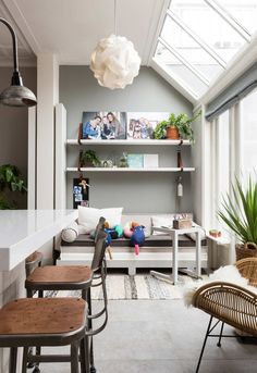 a living room filled with furniture and lots of plants on top of the bookshelves