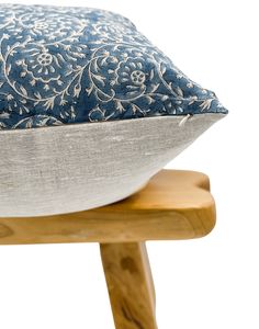 a blue and white pillow sitting on top of a wooden chair with a wood leg