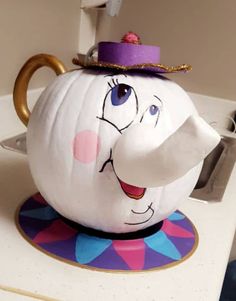 a teapot shaped like an elephant with a purple hat on it's head