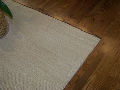 a white rug is on the floor next to a vase with a plant in it