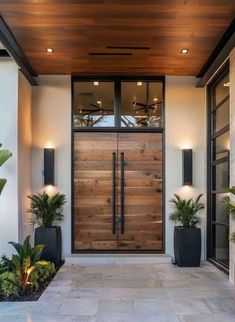 the front entrance to a modern home with two large planters and an entry door