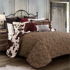 a bed with brown and white comforters in a room next to a wooden wall