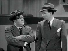 two men in suits and hats standing next to each other