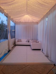 a living room with white curtains and lights on the ceiling is lit up by string lights