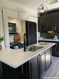 a large kitchen with black cabinets and white counter tops, an island in the middle