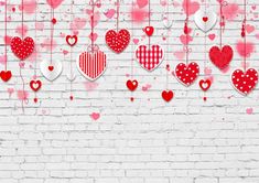 valentine's day background with red and white hearts hanging from strings on a brick wall