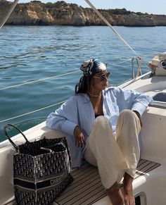 a woman sitting on the back of a boat with her purse in front of her